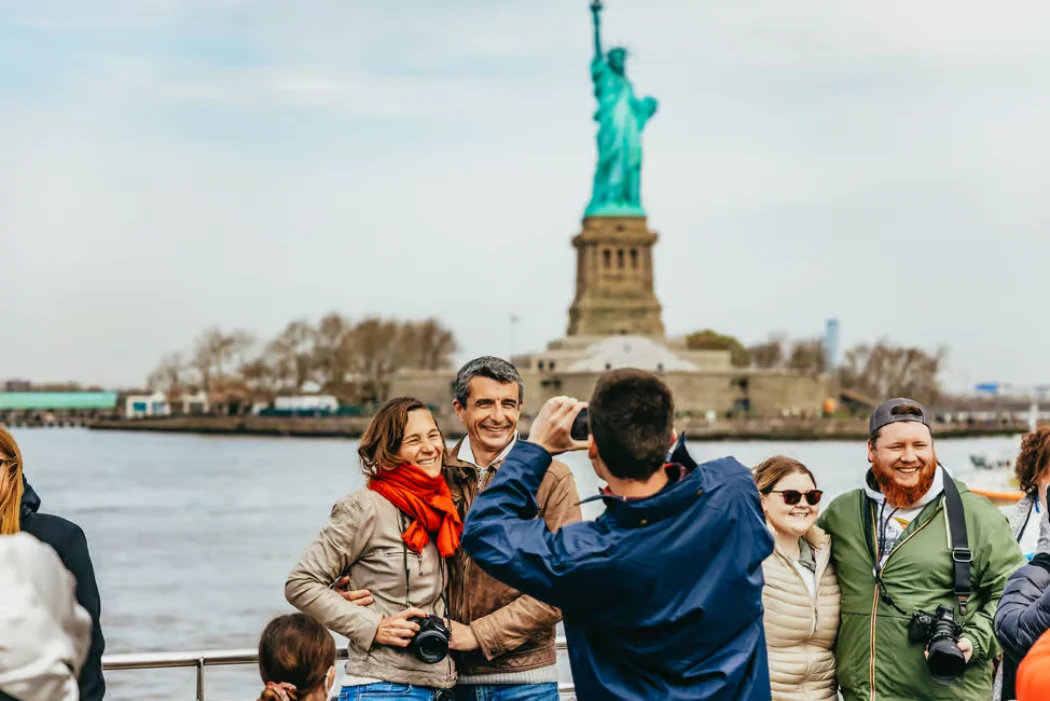 A couple posing on the NYC Boat Cruise with Lady Liberty in the background
