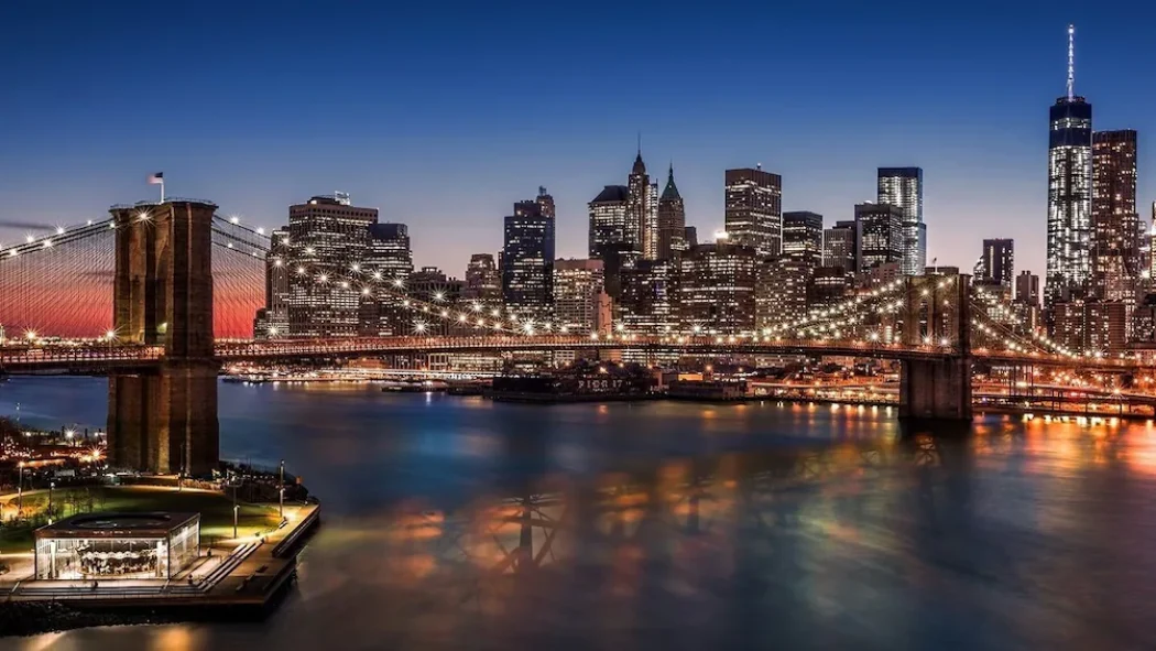 Brooklyn Bridge seen from the cruise at dusk, with the Manhattan skyline illuminated in the background