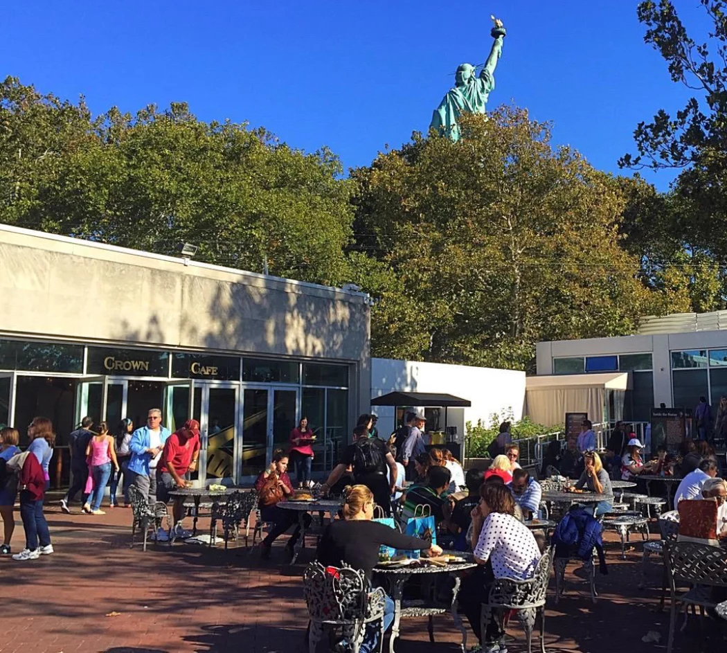 Visitors dining at the Crown Cafe with a view of the Statue of Liberty