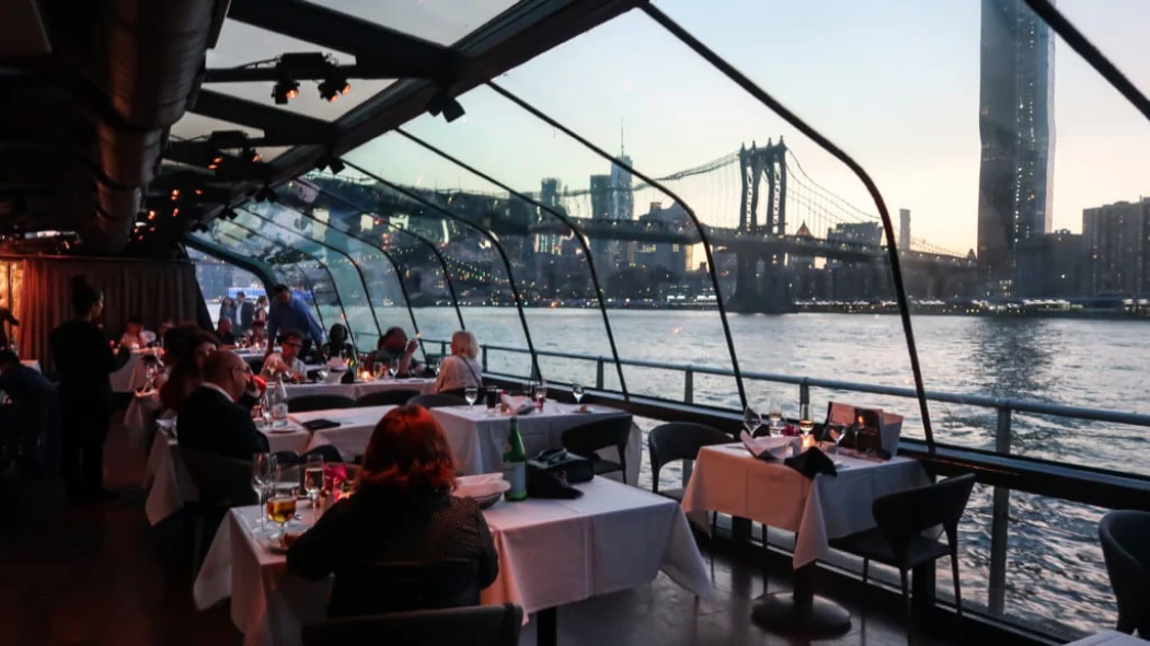 Visitors enjoying the Gourmet Dinner Cruise with the Brooklyn Bridge views