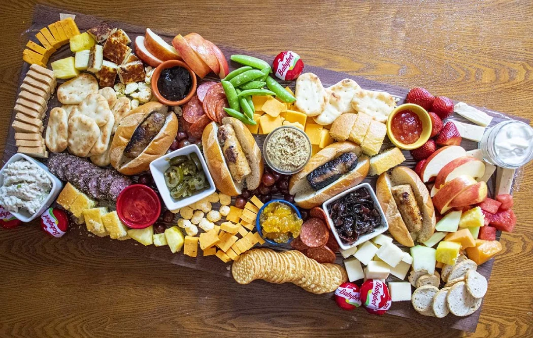 A charcuterie board filled with a selection of cheeses, meat delicacies, nuts, jam, and olives